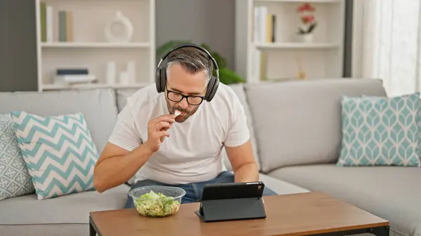 Siwowłosy Mężczyzna Sałatkę Używając Touchpada Słuchawek Domu — Zdjęcie stockowe