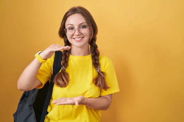 Mladá Běloška Oblečená Studentského Batohu Žlutém Pozadí Gestikuluje Rukama Velkým — Stock fotografie
