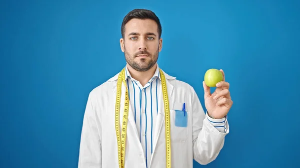 Junger Hispanischer Mann Diätassistentin Hält Apfel Über Isolierten Blauen Hintergrund — Stockfoto