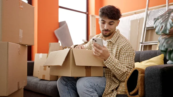 Junger Araber Packt Neuen Zuhause Mit Smartphone Pappschachtel Aus — Stockfoto