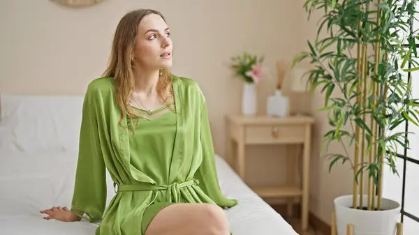 Mujer Rubia Joven Sentada Cama Con Cara Seria Dormitorio —  Fotos de Stock