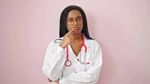 Afroamerikanische Ärztin Steht Mit Zweifelndem Gesichtsausdruck Vor Isoliertem Rosa Hintergrund — Stockfoto