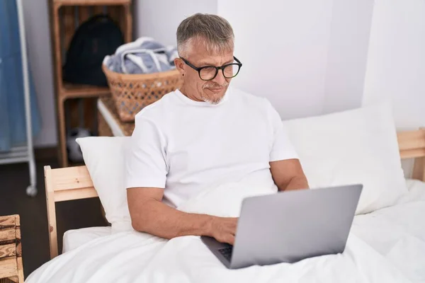Yatak Odasında Dizüstü Bilgisayar Kullanan Orta Yaşlı Kır Saçlı Bir — Stok fotoğraf
