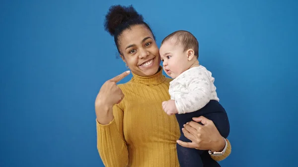 Mãe Filho Sorrindo Confiante Apontando Para Bebê Sobre Fundo Azul — Fotografia de Stock