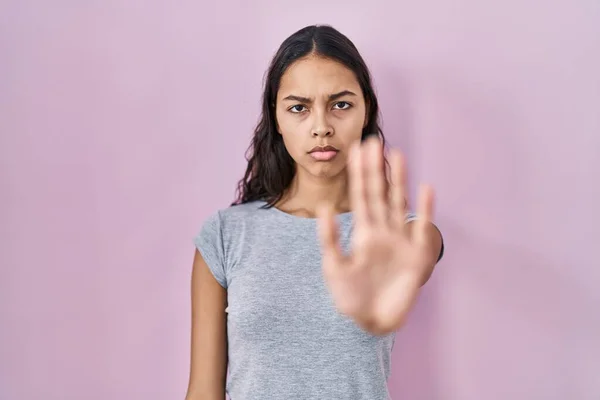 年轻的巴西女人穿着粉色背景的休闲T恤 停止手心唱着歌 用消极而严肃的手势警告人 — 图库照片