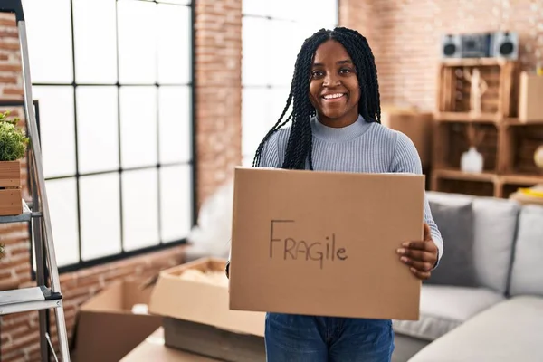 Afroamerikanerin Lächelt Zuversichtlich Und Hält Zerbrechliches Paket Neuen Zuhause — Stockfoto