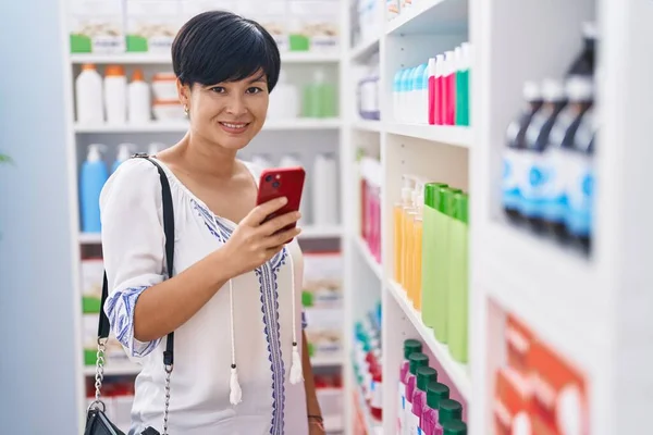 stock image Middle age chinese woman customer smiling confident using smartphone at pharmacy