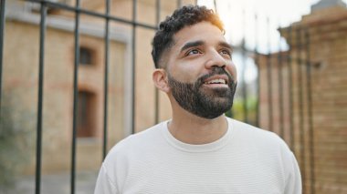Young hispanic man smiling confident looking to the sky at street