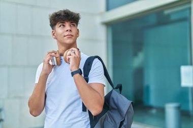 Üniversitede sırt çantası takarak gülümseyen genç İspanyol öğrenci.