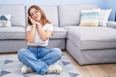 Genç, beyaz bir kadın oturma odasında yerde oturuyor. Yorgun uyuyor. Hayal kuruyor, birlikte poz veriyor ve gözleri kapalı gülümsüyor.. 