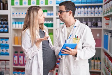 Erkek ve kadın eczacılar eczanede dokunmatik ped kullanıyorlar.