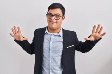 Down sendromlu genç İspanyol adam iş stili giyiniyor ve parmaklarını on numaraya doğrultuyor. Kendinden emin ve mutlu gülümsüyor.. 