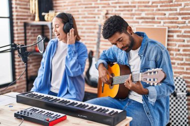 Klasik gitar çalan erkek ve kadın müzisyenler müzik stüdyosunda şarkı söylüyorlar.