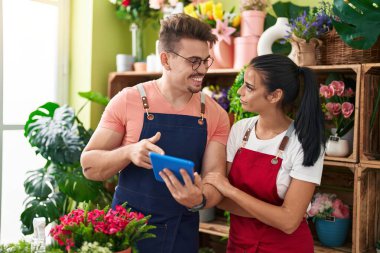 Çiçekçide çalışan erkek ve kadın çiçekçiler dokunmatik ped kullanıyorlar.
