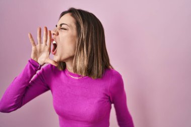 İspanyol bir kadın pembe arka planda durup el pençe divan çığlıklar atıyor. iletişim konsepti. 