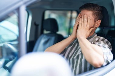 Young caucasian man stressed driving car at street