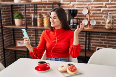 Genç, güzel, İspanyol bir kadın evdeki masada oturmuş video görüşmesi yapıyor.