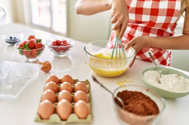 Genç ve güzel İspanyol kadın mutfakta yumurta karıştırıyor.