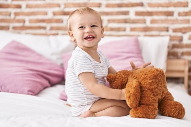 Sevimli çocuk yatak odasında oyuncak ayıyla oynuyor.