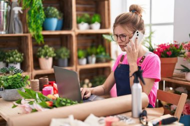 Çiçekçide bilgisayarla konuşan sarışın bir çiçekçi.
