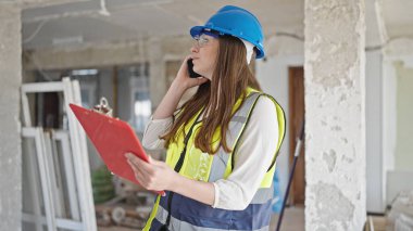 Şantiyede akıllı telefon okuyarak konuşan genç, güzel İspanyol mimar kadın.