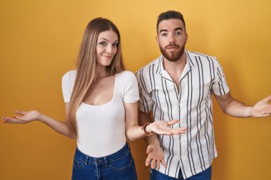 Sarı arka planda dikilen genç çift hiçbir şeyden habersiz ve kolları açık, hiçbir fikri yok.. 