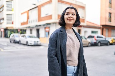 Gülümseyen genç bir kadın sokağın kenarına bakıyor kendinden emin.