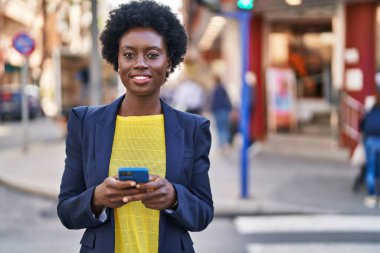 Young african american woman business executive using smartphone at street