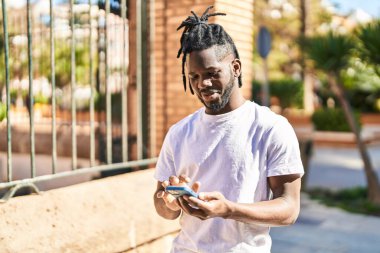 Afro-Amerikalı kadın sokakta akıllı telefon kullanarak kendine güveniyor.