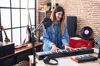 Genç İspanyol kadın müzisyen müzik stüdyosunda piyano çalıyor.