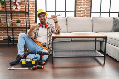 Sakallı, mutlu ve olumlu bir şekilde gülümseyen, başparmağıyla mükemmel ve onay işareti yapan bir İspanyol. 