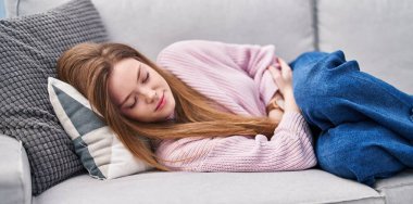 Beyaz bir kadın kanepede uzanıyor ve evinde uyuyor.