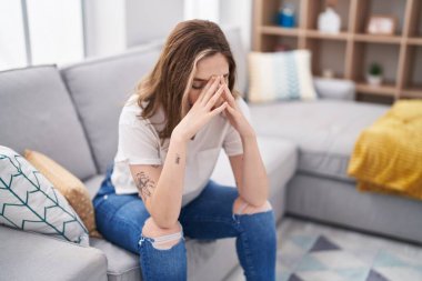 Young woman stressed sitting on sofa at home