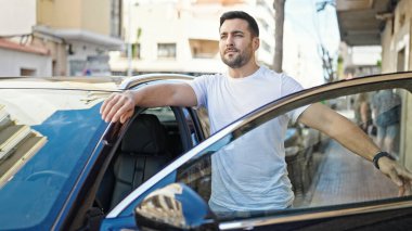 Young hispanic man opening car door at street