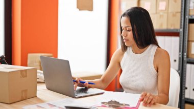 Young beautiful hispanic woman ecommerce business worker using laptop working at office