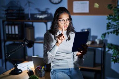 Geceleri dokunmatik ped kullanan genç Brezilyalı bir kadın ofiste çalışıyor. Parmakla işaret ediyor ve kızgın bir ifade sergiliyor. 
