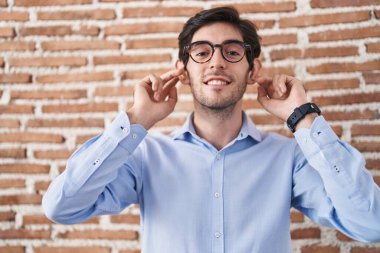 Duvarın arkasında dikilen genç İspanyol adam gülümsüyor parmaklarıyla kulaklarını çekiyor, komik bir jest. deneme sorunu 