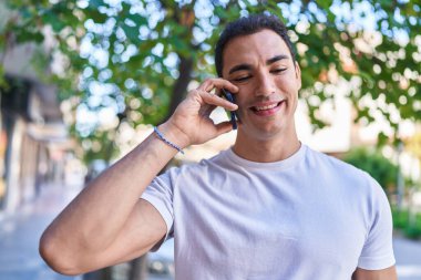 Genç İspanyol adam gülümsüyor. Kendine güveniyor. Sokakta akıllı telefondan konuşuyor.