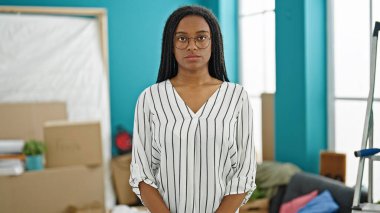 Yeni evinde ciddi bir ifadeyle duran Afrikalı Amerikalı kadın.
