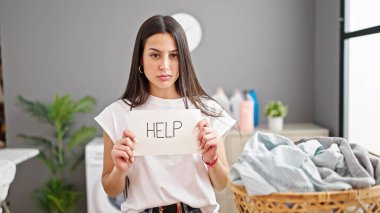 Çamaşır yıkayan genç ve güzel İspanyol kadın çamaşır odasında kağıt taşımaya yardım ediyor.