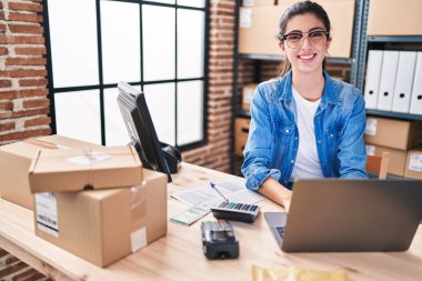 Young beautiful hispanic woman ecommerce business worker using laptop working at office