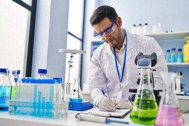 Genç İspanyol bilim adamı laboratuvarda sıvı yazım raporunu ölçüyor.