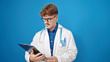 Genç İspanyol doktor, mavi arka planda ciddi bir yüzle panoda doküman okuyor.