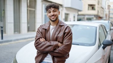 Arabasının yanında duran genç bir Arap caddede çapraz hareketler yapıyor.