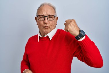 Senior man with grey hair standing over isolated background strong person showing arm muscle, confident and proud of power 