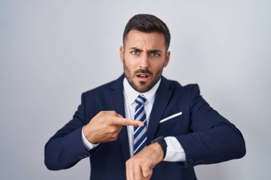 Yakışıklı İspanyol takım elbiseli ve kravatlı adam acele edip saati, sabırsızlığı ve gecikmeyi gösteriyor. 