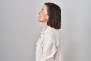 Middle age hispanic woman standing over isolated background looking to side, relax profile pose with natural face and confident smile. 