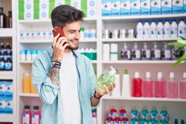 Genç İspanyol adam eczanede akıllı telefondan el ele tutuşup konuşuyor.