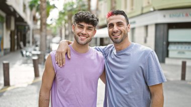 Two men couple smiling confident hugging each other at street