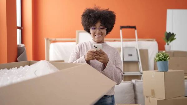 Young African American Woman Unpacking Cardboard Box Using Smartphone New — Stock Photo, Image